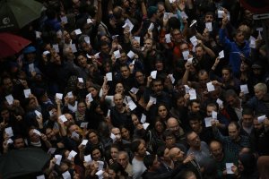 Participantes no referendo mostram o seu boletim de voto diante da polícia que os impede de entrar no colégio Ramon Llull