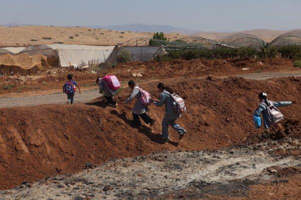 <p>Crianças palestinianas atravessam uma vala cavada pelo exército israelita numa estrada que separa a aldeia de Atouf de Khirbet Ras al-Ahmar, ao regressarem da escola na aldeia de Atouf, no Vale do Jordão, a sudeste de Tubas. Desde 2025 que as forças israelitas têm vindo a demolir estruturas residenciais e agrícolas pertencentes a famílias palestinianas na zona de Ras al-Ahmar. 21 de Setembro de 2026.</p>