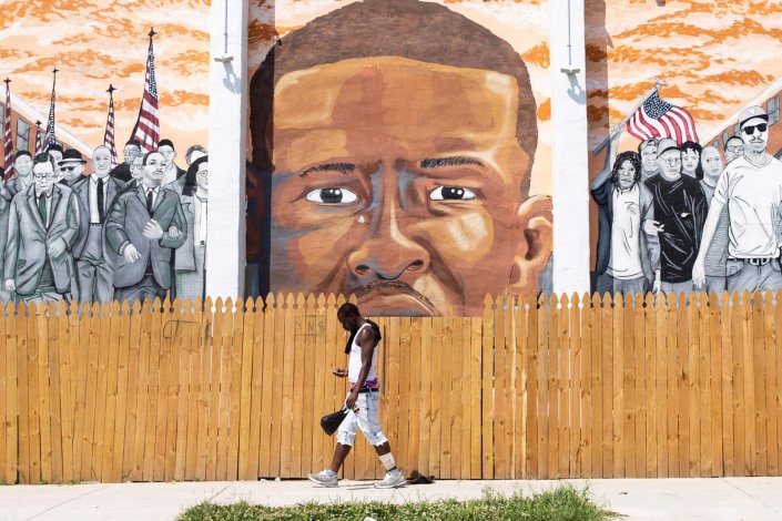 Um homem passa por um mural de Freddie Gray perto do local onde Gray foi espancado pela polícia em 2015. Donald Trump foi acusado de racismo depois de chamar à cidade uma caixa de lixo repugnante, infestada de ratos e roedores. Baltimore, EUA.