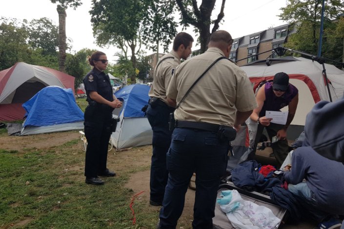 Guardas-florestais entregam notificações aos sem-abrigo que vivem há cerca de um ano em tendas no parque florestal de Oppenheimer, na cidade de Vancouver, Colúmbia Britânica, Canadá, a 19 de Agosto de 2019.