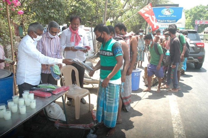 Militantes comunistas entregam comida a trabalhadores migrantes que passam pela cidade de Vijayawada, no estado indiano de Andhra Pradesh