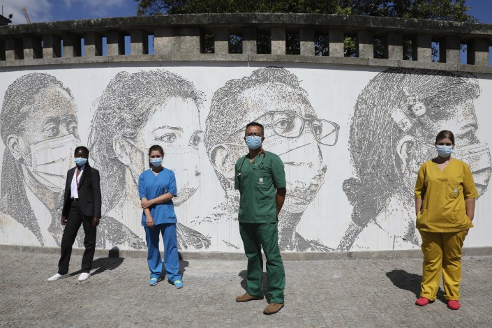 Os trabalhadores da saúde (da esquerda para a direita) Cristina Teixeira, Raquel Queirós, David Andrade e Idalina Ramos, posam em frente do mural onde se encontram representados, no Hospital de São João, no Porto, a 19 de Junho de 2020. O artista urbano VHILS – assinatura de Alexandre Farto – desenhou um mural com dez rostos de trabalhadores da saúde naquele hospital portuense, homenageando aqueles que, no Serviço Nacional de Saúde, estiveram na linha da frente do combate à pandemia do coronavírus