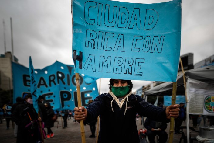 Manifestante empunha cartaz «Cidade rica com fome» durante um dia nacional de protesto promovido pelos colectivos dos bairros populares contra a falta de comida nas cantinas para pobres, em Buenos Aires, Argentina, a 24 de Julho de 2020.As organizações sociais denunciam a insegurança alimentar no país, após quatro meses de quarentena devido à pandemia da COVID-19 