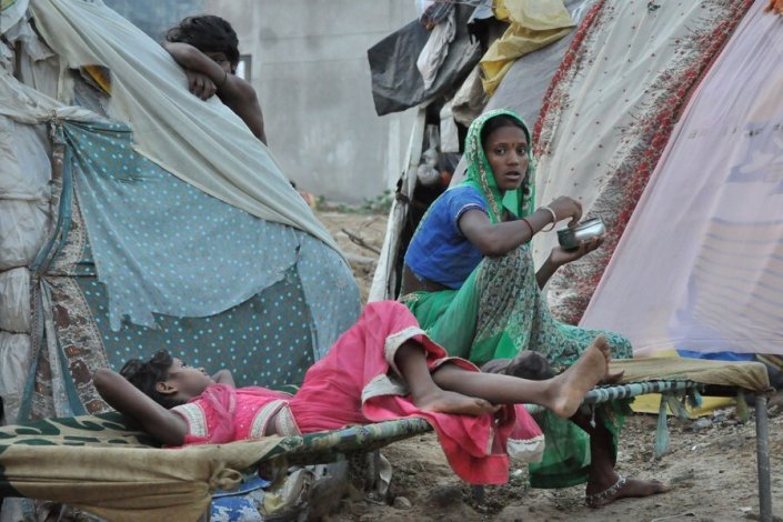 Uma trabalhadora com duas crianças nas barracas de Gurugram, cidade satélite de Nova Déli, no estado de Haryana, 26 de Julho de 2020 