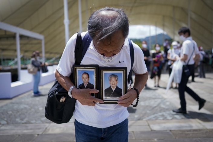 Toru Nagata, segura os retratos dos seus pais, Rokutaro e Hatsune, sobreviventes do bombardeamento atómico de 1945, enquanto faz as suas orações seus pais no Parque da Paz, em Nagasáqui, a 9 de Agosto de 2020, durante as cerimónias que assinalaram o 75.º aniversário do bombardeamento atómico que arrasou a cidade e causou mais de 70 mil mortos civis e 150 militares
