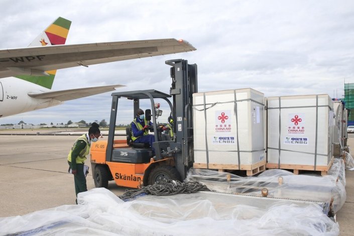 Trabalhadores descarregam as vacinas doadas pela China no Aeroporto Internacional Robert Gabriel Mugabe, em Harare, capital do Zimbabwe, no dia 15 de Fevereiro de 2021 