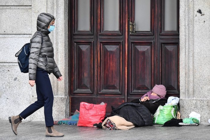 Um transeunte passa ao lado de um sem-abrigo, no centro de Génova, Itália, a 4 de Março de 2021. A pobreza absoluta em 2020 atingiu 2 milhões de famílias e 5,6 milhões de pessoas no país, com um novo máximo de crescimento desde 2005.