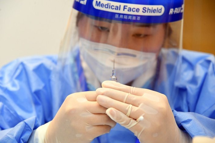 Um trabalhador da Saúde prepara uma vacina num centro temporário de vacinação contra a Covid-19, numa empresa do distrito de Haidian, Pequim, a 22 de Fevereiro de 2021