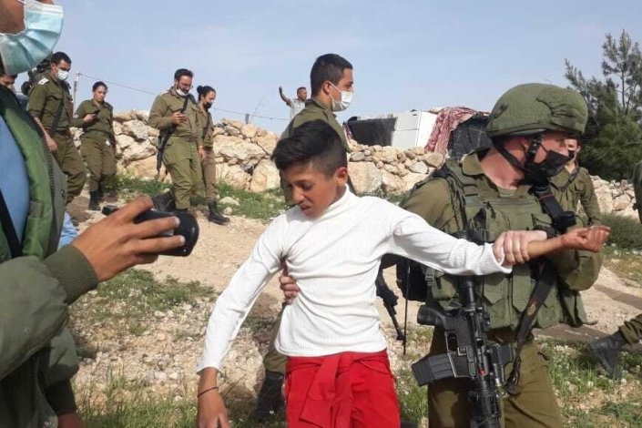 Um soldado israelita detém um rapaz palestiniano, juntamente com outros quatro, perto do posto avançado de Havot Maon, na Margem Ocidental ocupada, a 11 de Março de 2021
