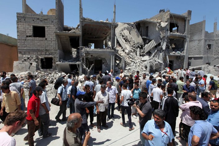 Habitantes locais mostram a jornalistas casas destruídas e corpos de civis mortos por bombardeamentos da coligação da NATO, em Tripoli, a 19 de Junho de 2011