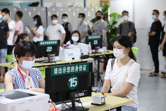 Uma trabalhadora regista informação sobre as pessoas que vão ser inoculadas num centro de vacinação contra a Covid-19 no distrito de Haizhu, em Guangzhou, província de Guangdong (Sul da China), a 19 de Junho de 2021