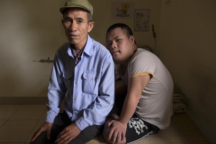 Um antigo soldado vietnamita, Nguyen Hong Phuc, de 63 anos, senta-se na cama com o seu filho, Nguyen Dinh Loc, de 20 anos, que recupera de uma operação a um tumor numa instituição para vítimas do Agente Laranja/dioxina