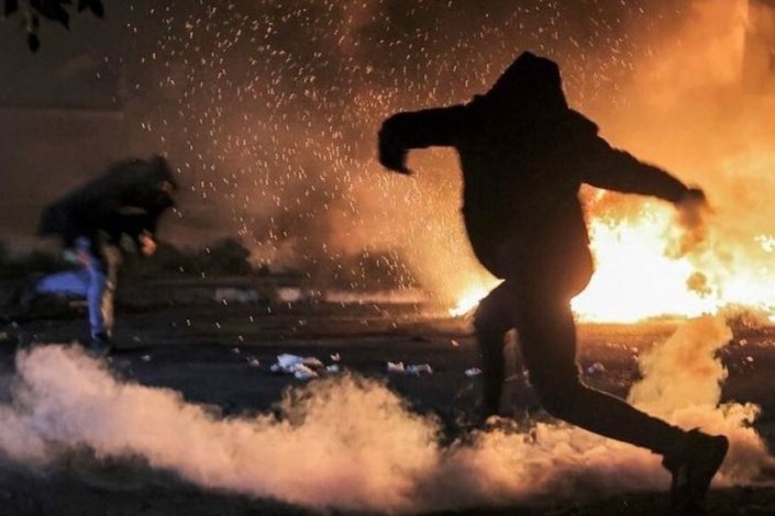 Um palestiniano atira uma lata de gás lacrimogéneo de volta para as forças israelitas, durante os confrontos que se registaram perto da cidade Nablus no dia 25 de Dezembro de 2021 