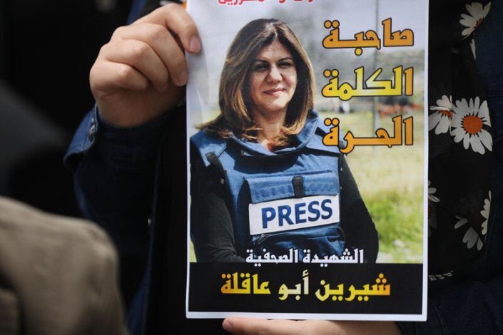Um jornalista segura um cartaz com a imagem de Shireen Abu Akleh durante um protesto contra o seu assassinato, em Gaza, dia 11 de Maio