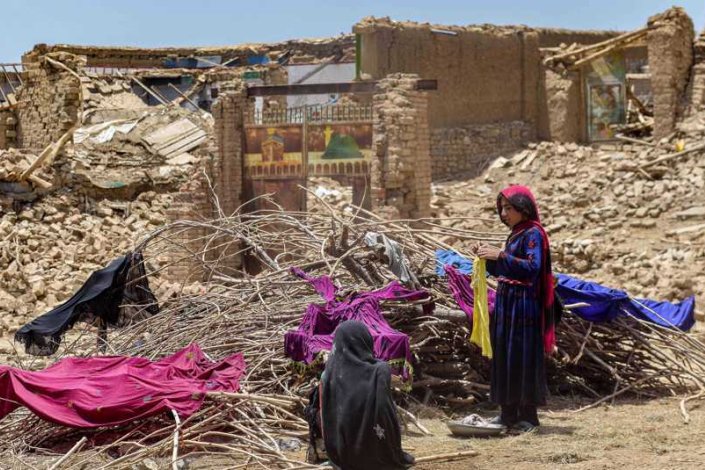 Mulheres afegãs junto às ruínas de casas atingidas por um sismo no distrito de Bermal, província de Paktika, a 23 de Junho de 2022 