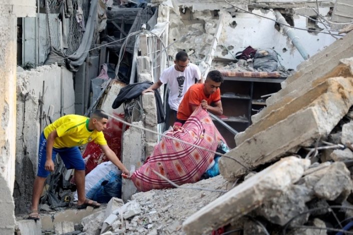 Palestinianos retiram pertences entre os destroços da sua casa, na sequência de um ataque aéreo israelita em Rafah, Faixa de Gaza cercada, a 7 de Agosto de 2022