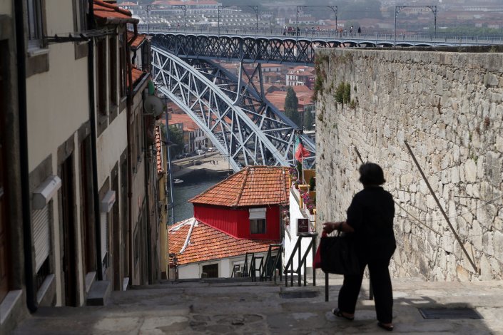 Uma mulher desce as escadas dos Guindais. Ao longe, a ponte D. Luís, na zona ribeira do Porto