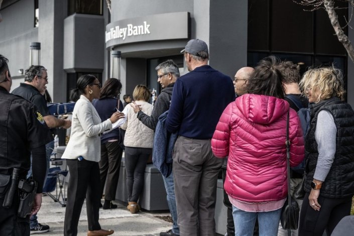 Uma funcionária do Silicon Valley Bank estende impressos aos clientes que tentam levantar os seus depósitos após o anúncio do colapso do banco. Santa Clara, Califórnia, EUA, Março de 2023