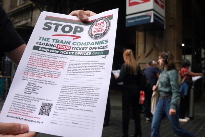 Um activista do sindicato RMT mostra, a 13 de Julho de 2023, um folheto numa acção de protesto junto à estação de Glasgow, na Escócia, contra o anúncio de encerramento em massa de bilheteiras