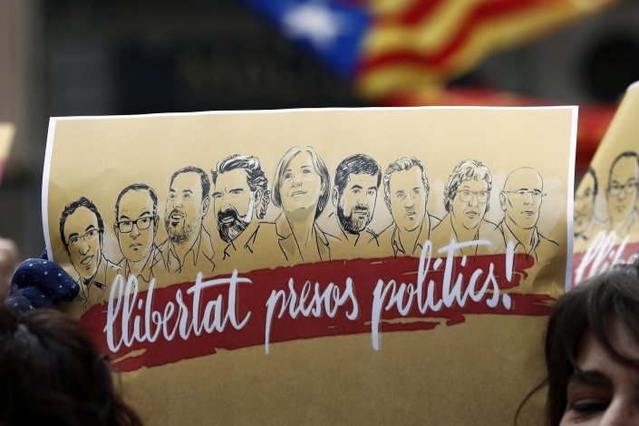 Cartaz onde se lê «Liberdade aos presos políticos», com os rostos dos líderes catalães encarcerados, empunhado por um participante numa concentração no centro de Pamplona (Navarra, Espanha). 25 de Março de 2018