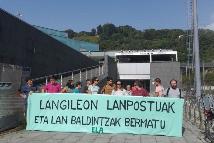 Trabalhadores do Polidesportivo Usabal Kiroldegia, em Tolosa, em greve, junto a uma faixa em que se lê «Garantir os postos e as condições de trabalho»