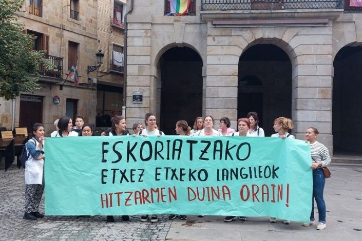 Trabalhadoras mobilizadas junto a uma faixa em que se lê: «Trabalhadoras do apoio domiciliário de Eskoriatza. Acordo digno já»