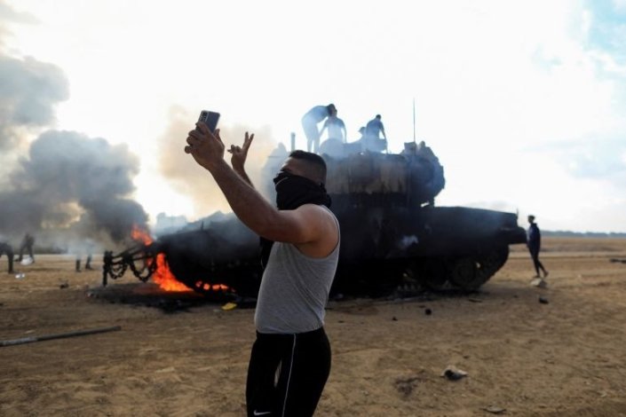 Um palestiniano tira uma fotografia junto a um tanque israelita destruído, a 7 de Outubro de 2023
