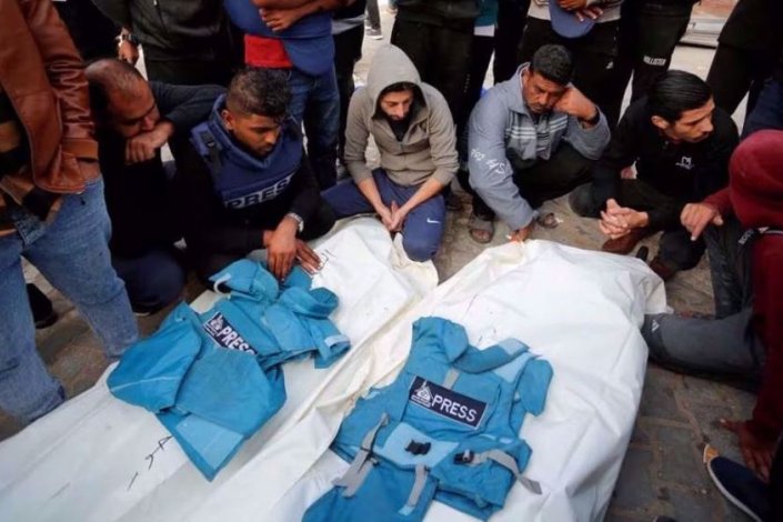 Um grupo de palestinianos rodeia os corpos sem vida dos jornalistas Hassouna Sleem e Sary Mansour, mortos num ataque israelita contra uma casa, num hospital da região central da Faixa de Gaza