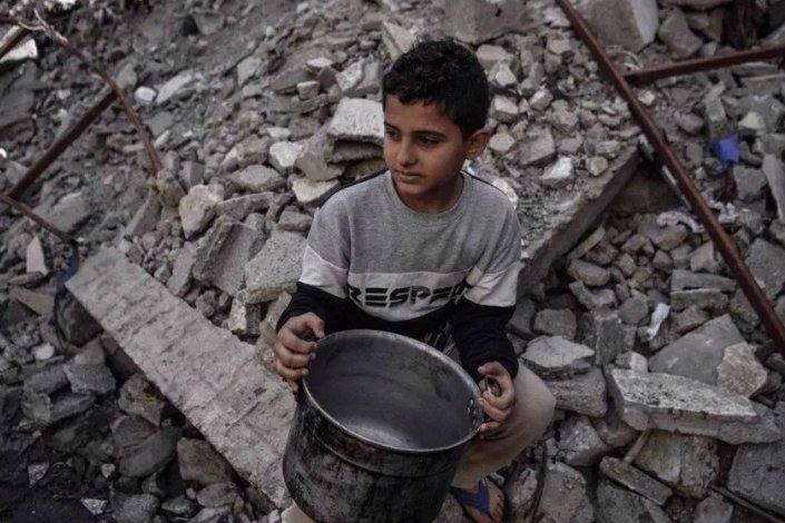 Uma criança palestiniana segura uma panela vazia, à espera de receber comida distribuída por voluntários em Rafah, no Sul da Faixa de Gaza, a 22 de Dezembro de 2023