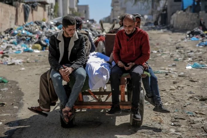 Grupo de palestinianos com o corpo de um dos mortos no ataque israelita às pessoas que esperavam por ajuda na Cidade de Gaza, a 29 de Fevereiro de 2024