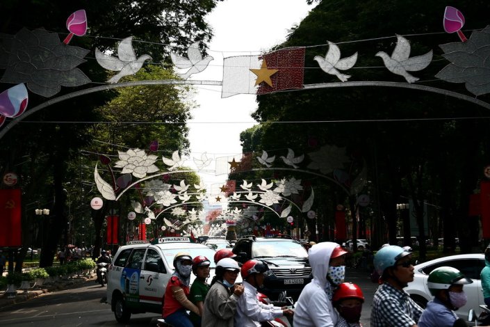 Vietnamitas circulam numa avenida engalanada para as comemorações do Dia da Reunificação e da Libertação do Sul, na Cidade de Ho Chi Minh, em Abril de 2016 
