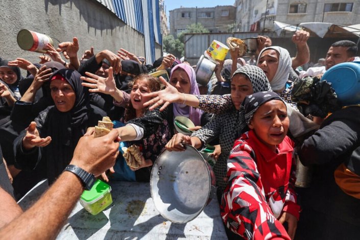 Palestinianos procuram obter algum alimento numa cozinha humanitária gerida pelo Programa Alimentar Mundial das Nações Unidas, no campo de refugiados de Nuseirat, Faixa de Gaza, a 26 de Abril de 2025