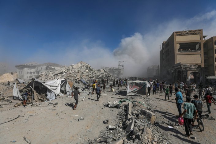 Palestinianos passam por entre os escombros do edifício residencial al-Roya, na zona Oeste da cidade de Gaza, na Faixa de Gaza, após um ataque aéreo israelita, a 8 de setembro de 2025