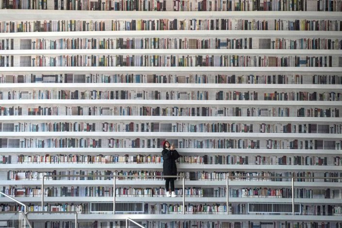 Um visitante tira fotos na biblioteca de Tianjin Binhai. O edifício futurista surpreendeu os amantes dos livros em todo o mundo, com as suas prateleiras ondulantes e brancas que se elevam do chão ao tecto. 17 de Novembro de 2017, Tianjin, China.
Fotografia: Fred Dufour