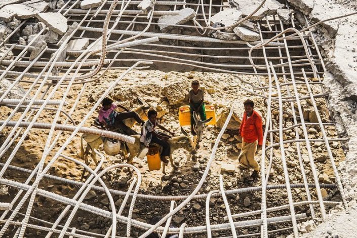  Um homem e os seus filhos num zona bombardeada de Hudaydah
