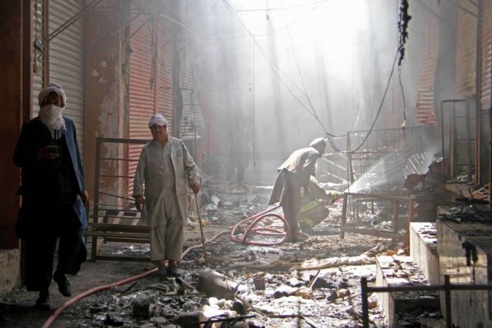 Um bombeiro afegão espalha água sobre lojas incendiadas durante o ataque talibã a Ghazni, Afeganistão, em Agosto de 2018.