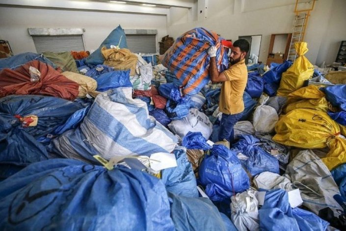 Um trabalhador dos serviços postais palestinianos movimenta-se por entre sacos de correio remontando a 2010, até agora retidos pelo Estado de Israel na central internacional de Jericó, na Palestina ocidental, em Agosto de 2018. Durante oito anos Israel reteve correio destinado à Palestina, incluindo cadeiras de rodas e brinquedos.