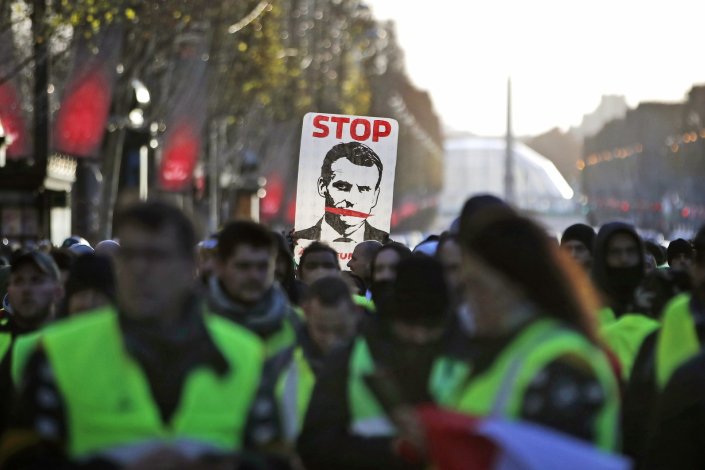 Um manifestante empunha uma pancarta onde se lê «Stop», com a figura do presidente francês, Emmanuel Macron, em Paris, França. 8 de Dezembro de 2018