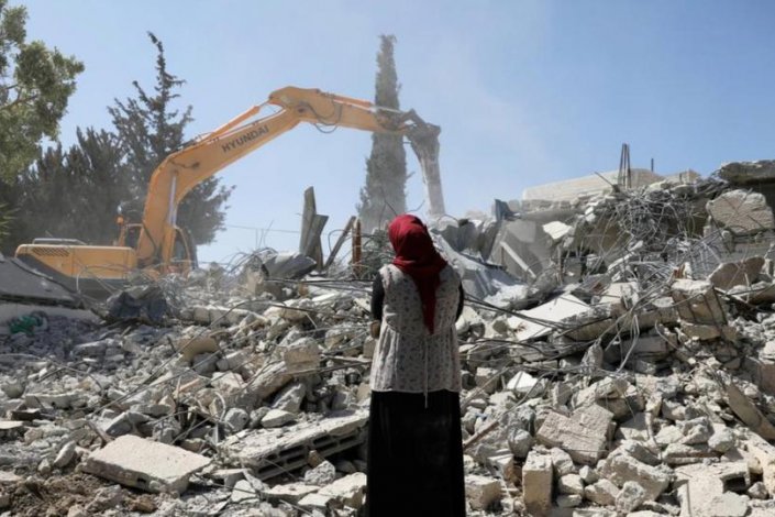 Uma mulher palestiniana olha para as ruÃ­nas da sua casa demolida, no bairro de Beit Hanina, em JerusalÃ©m Oriental 