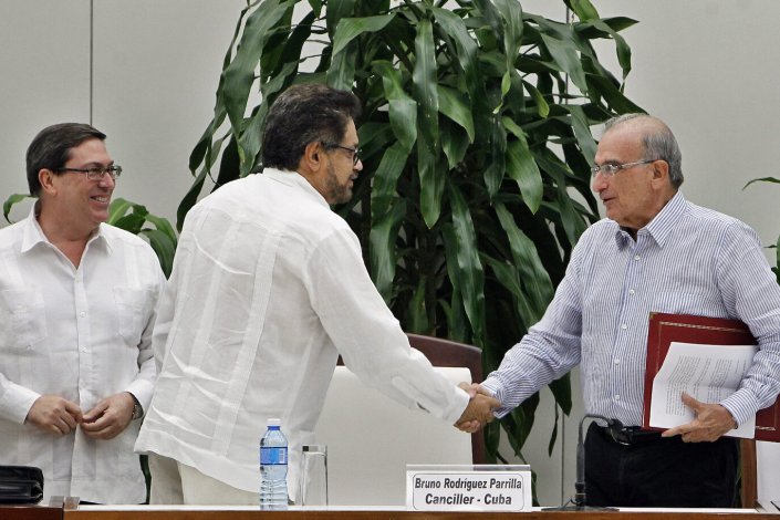 Em Havana, o ministro cubano dos negócios estrangeiros, Bruno Rodriguez Parilla, assiste ao cumprimento entre o porta-voz das FARC-EP, Iván Márquez, e o representante do governo colombiano, Humberto de la Calle, na cerimónia de assinatura do novo acordo de paz na Colômbia. 12 de Novembro de 2016