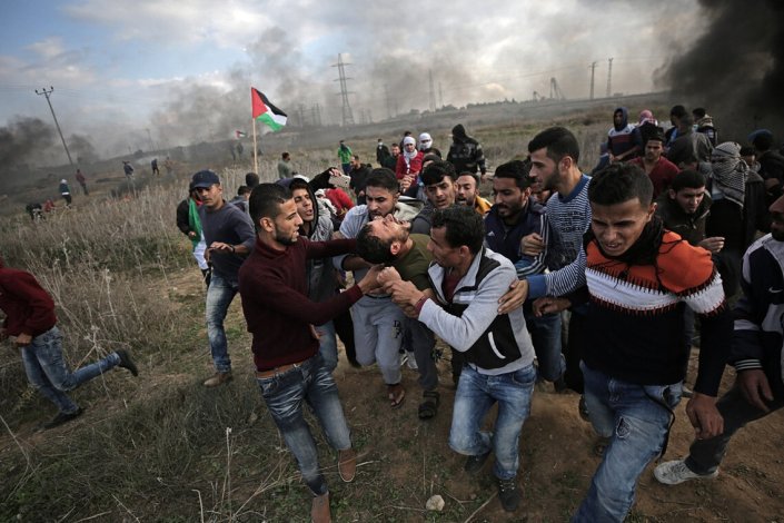 Um grupo de palestinianos leva um homem ferido perto da fronteira com Israel, na Faixa de Gaza