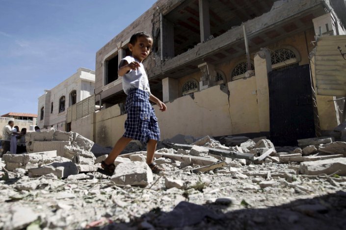 Uma criança caminha no meio de edifícios destruídos pela aviação saudita, no Iémen