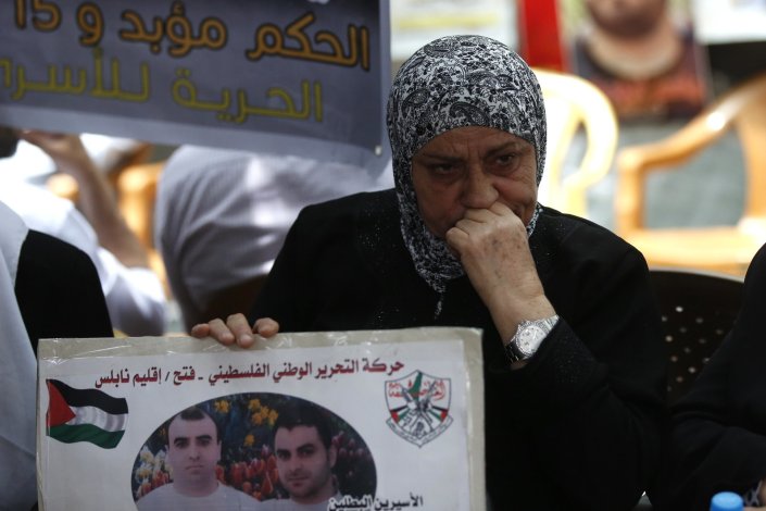 Uma palestiniana segura o retrato de familiares presos em Israel, actualmente em greve de fome, numa acção de solidariedade em Nablus (Margem Ocidental). 14 de Maio de 2017