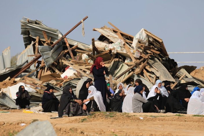 Mulheres palestinianas sentadas junto a estruturas demolidas na aldeia beduína de Umm al-Hiran, na região do Negev