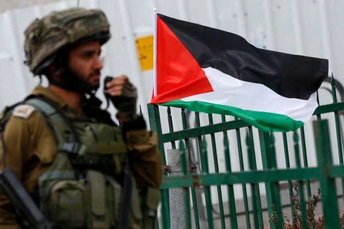 Soldado israelita e bandeira da Palestina em Hebron, na Margem Ocidental ocupada, durante protestos contra o reconhecimento, pela administração norte-americana, de Jerusalém como capital de Israel